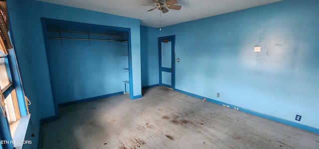 unfurnished bedroom featuring baseboards, a closet, wood finished floors, and a ceiling fan