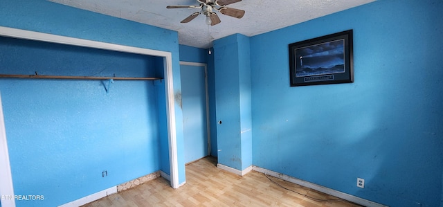 unfurnished bedroom featuring baseboards, a textured ceiling, ceiling fan, a closet, and wood finished floors