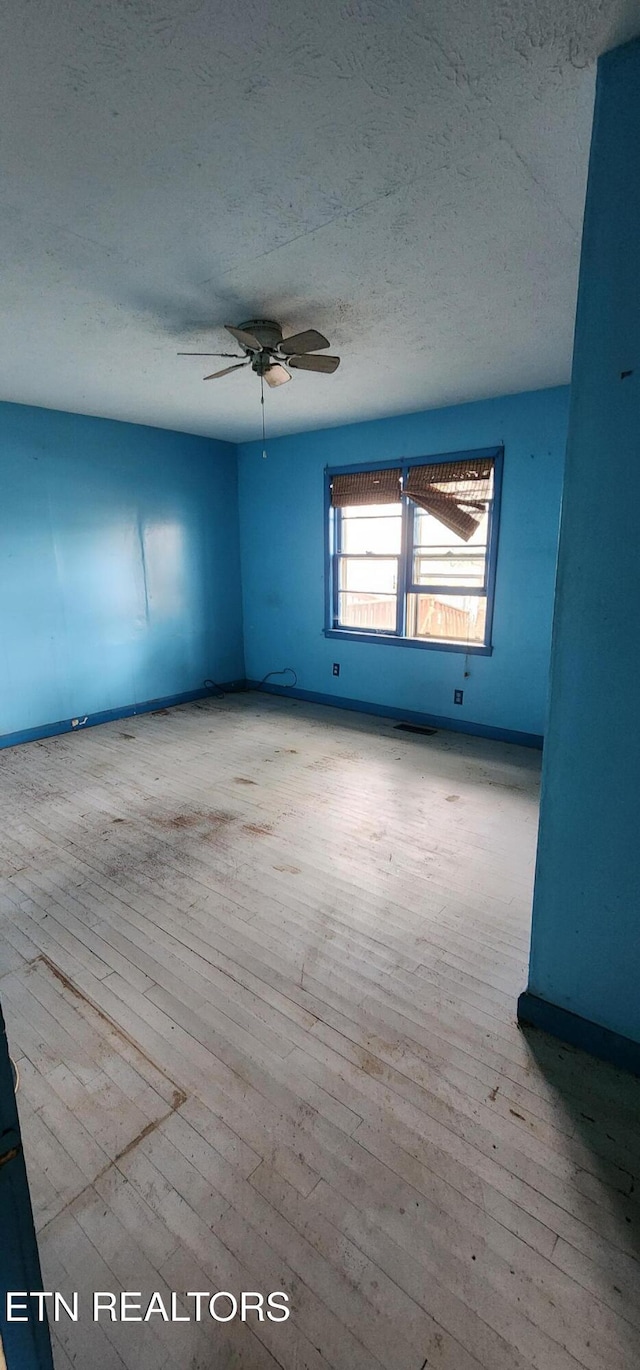 spare room with a textured ceiling, a ceiling fan, and wood-type flooring