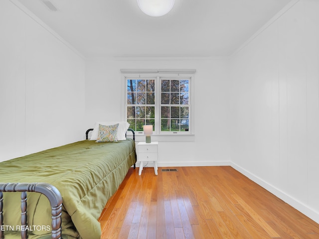 bedroom featuring ornamental molding, hardwood / wood-style flooring, baseboards, and visible vents