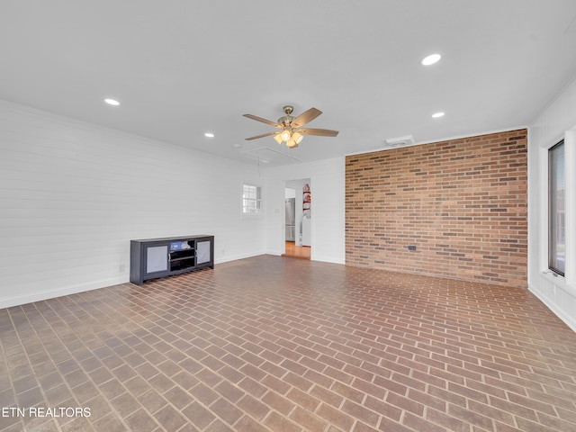 unfurnished living room featuring recessed lighting, baseboards, brick floor, brick wall, and a ceiling fan