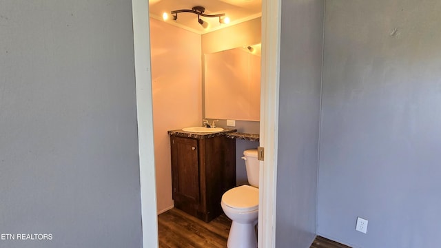 half bath featuring toilet, vanity, and wood finished floors