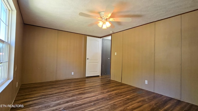 unfurnished bedroom featuring a closet, dark wood-style flooring, a textured ceiling, and ceiling fan