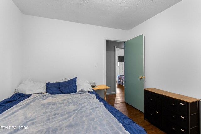 bedroom featuring a textured ceiling and dark wood finished floors