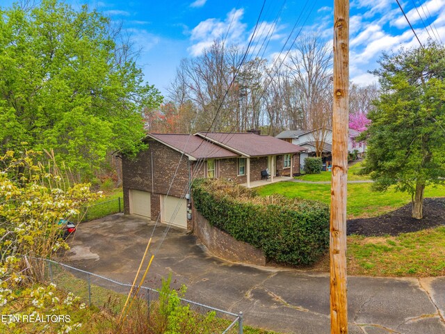 ranch-style home with fence, a garage, brick siding, roof with shingles, and driveway