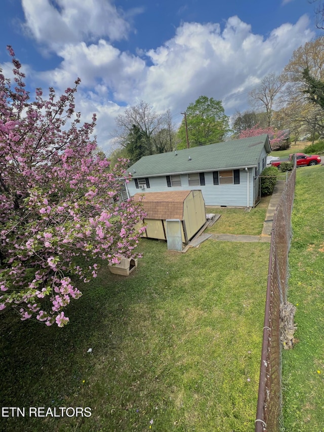 exterior space with a storage unit, a lawn, a shingled roof, and an outdoor structure