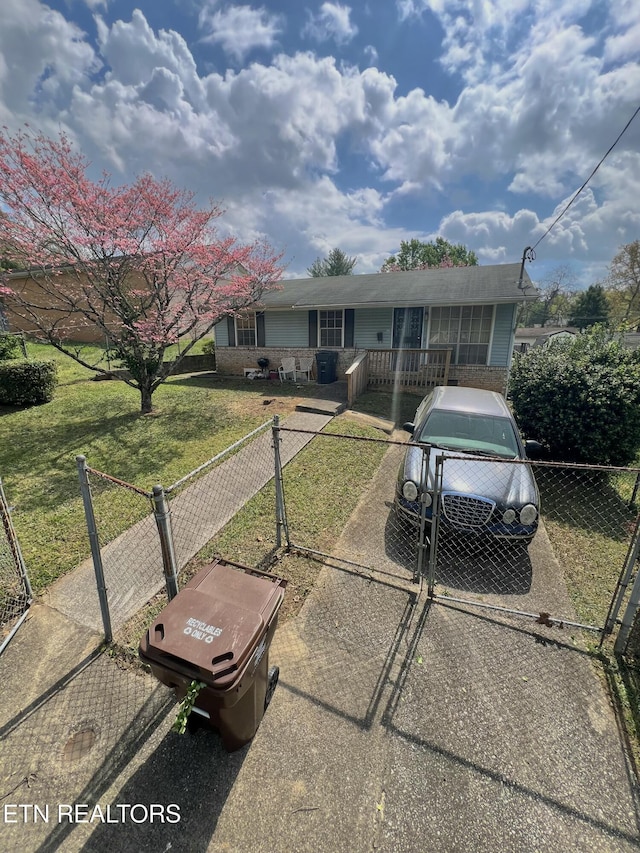 view of front of property featuring a gate, driveway, a fenced front yard, and a front lawn