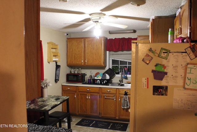 kitchen with light countertops, a ceiling fan, a sink, black microwave, and freestanding refrigerator