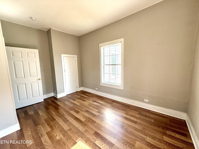 unfurnished bedroom with dark wood-style floors and baseboards
