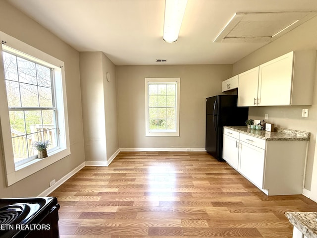kitchen with white cabinets, light wood-style flooring, freestanding refrigerator, and baseboards