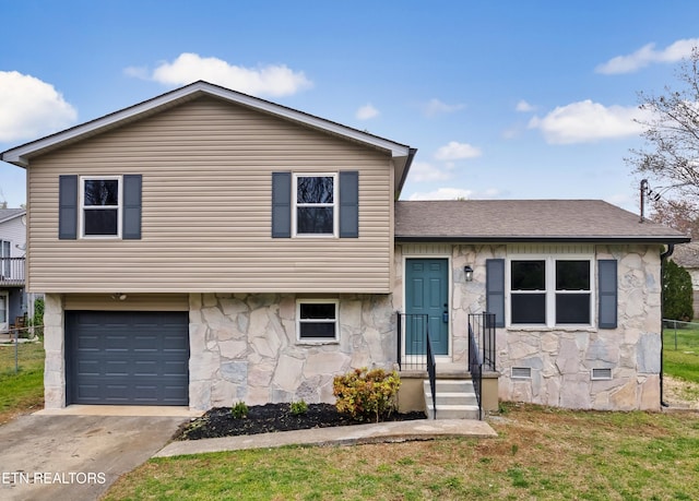 split level home with a front yard, stone siding, concrete driveway, an attached garage, and a shingled roof