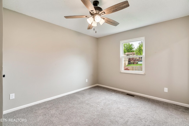 carpeted spare room with baseboards, visible vents, and a ceiling fan
