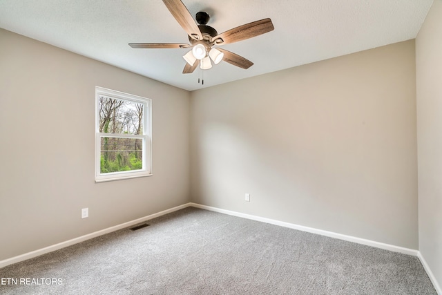 carpeted spare room featuring visible vents, baseboards, and ceiling fan