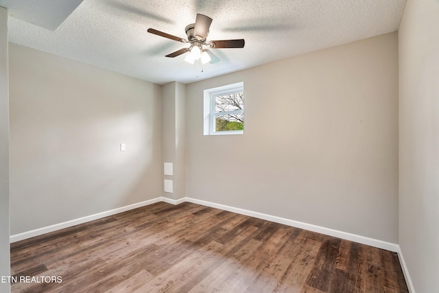 empty room featuring dark wood finished floors, baseboards, a ceiling fan, and a textured ceiling