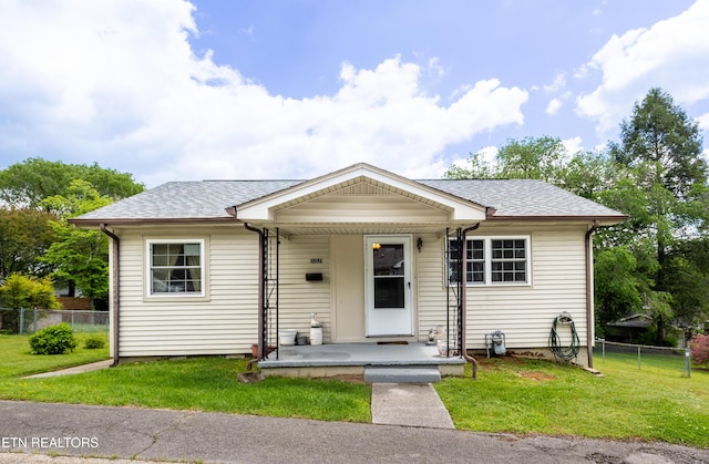 bungalow-style house featuring fence, a shingled roof, and a front lawn