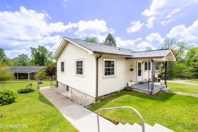 view of front of home with fence, roof with shingles, and a front lawn