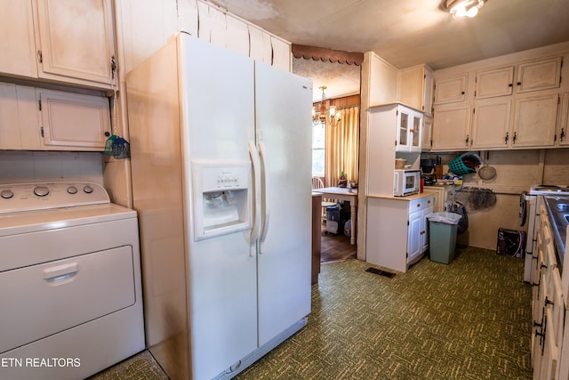 kitchen with light countertops, dark floors, a notable chandelier, washer / dryer, and white appliances