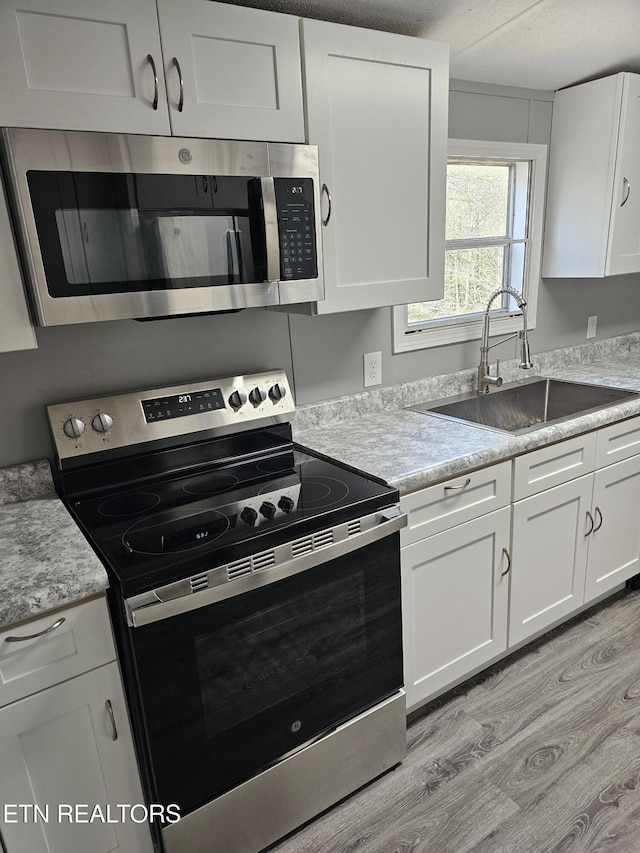367 Mcjunkin Rd, Tellico Plains, TN 37385 - kitchen featuring white cabinets, a sink, stainless steel appliances, and light wood finished floors