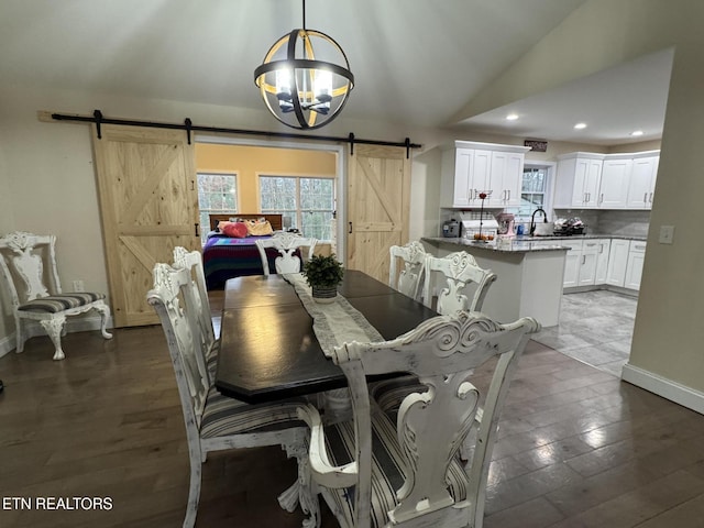 dining space with a chandelier, a barn door, wood finished floors, lofted ceiling, and recessed lighting
