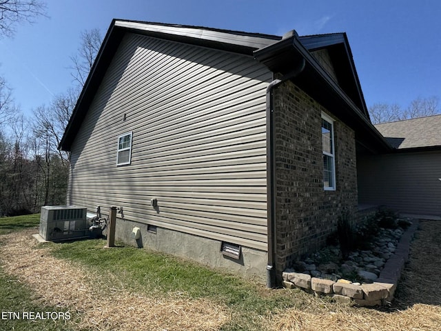 view of home's exterior featuring brick siding, crawl space, and central AC unit