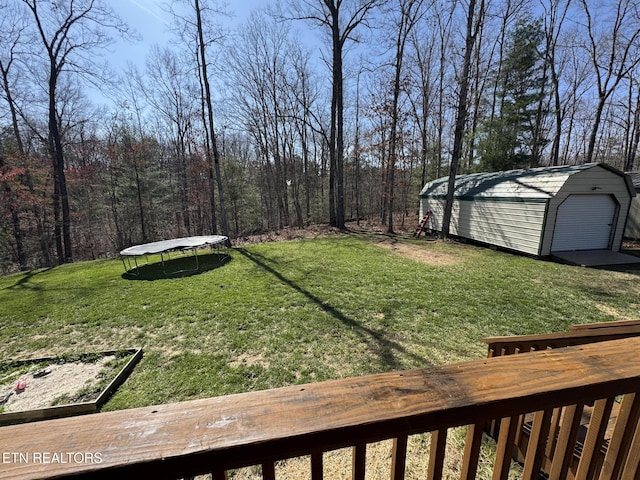 view of yard featuring a trampoline and an outbuilding