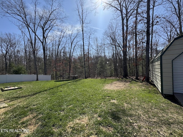 view of yard featuring fence and a wooded view