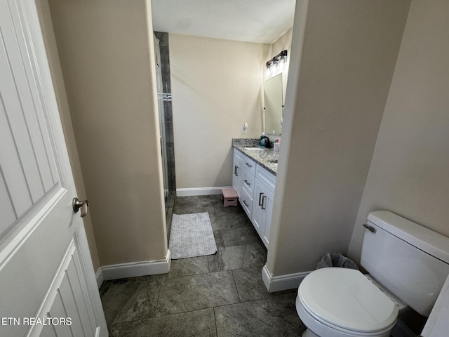 full bath featuring baseboards, toilet, vanity, and a shower stall