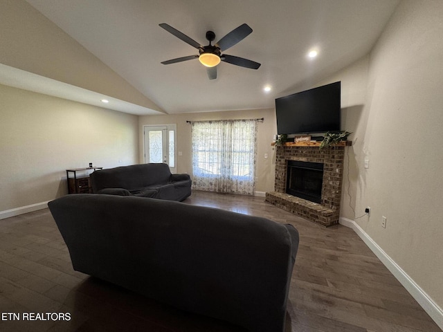 living area featuring a fireplace, a ceiling fan, vaulted ceiling, and wood finished floors