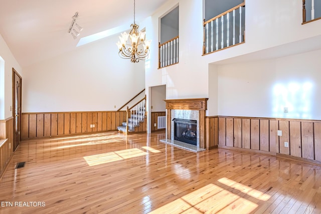 unfurnished living room featuring stairs, visible vents, wainscoting, and wood-type flooring