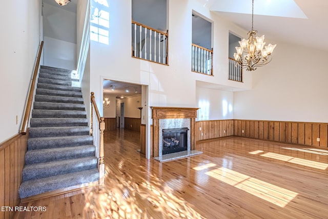 unfurnished living room with hardwood / wood-style floors, wood walls, stairway, and wainscoting