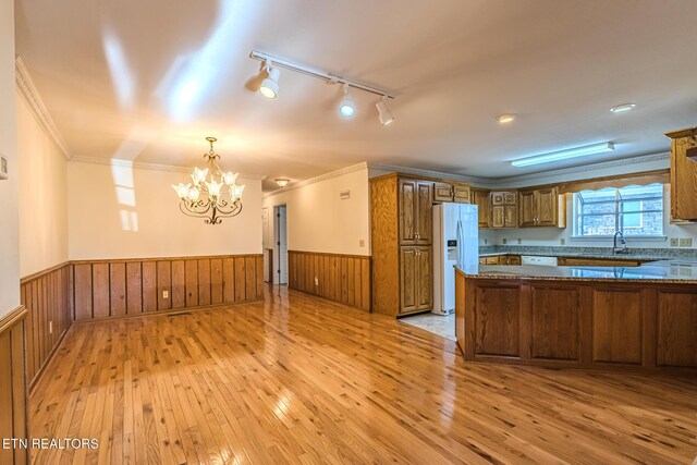 kitchen featuring light wood-type flooring, white appliances, a chandelier, brown cabinets, and wainscoting