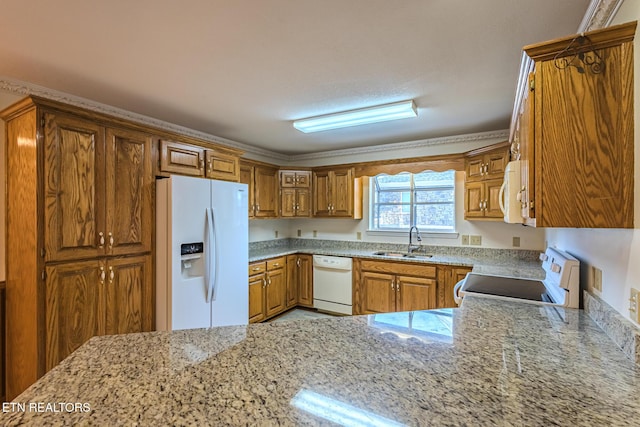 kitchen featuring white appliances, light stone counters, brown cabinets, and a sink