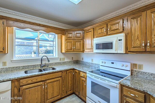 kitchen featuring a sink, brown cabinetry, and white appliances