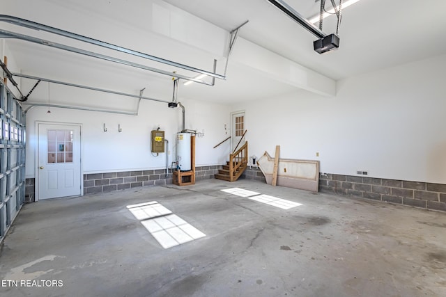 garage featuring water heater, concrete block wall, and a garage door opener