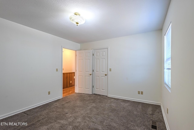 unfurnished bedroom with multiple windows, visible vents, carpet floors, and baseboards