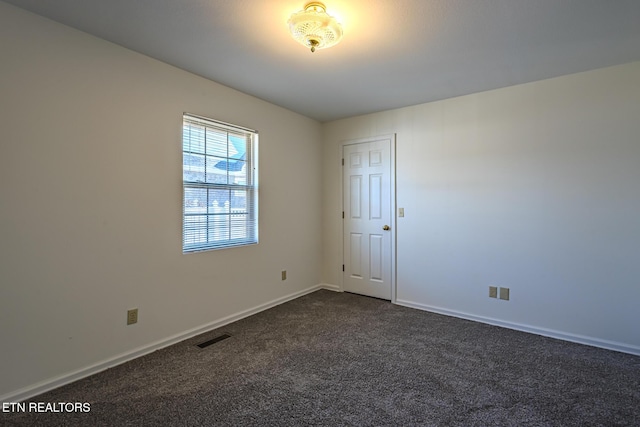 empty room featuring baseboards, visible vents, and dark colored carpet