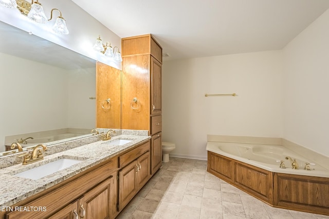 bathroom with a jetted tub, toilet, double vanity, and a sink