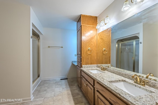 full bathroom with a stall shower, double vanity, baseboards, and a sink