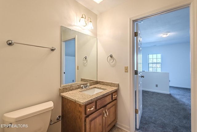 bathroom featuring baseboards, toilet, and vanity