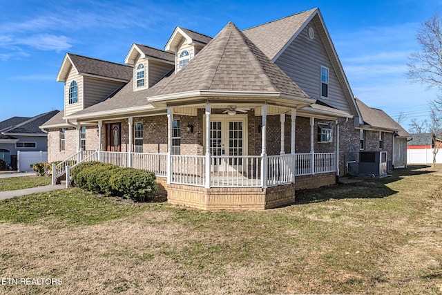 view of front of house featuring roof with shingles, french doors, a front yard, ceiling fan, and brick siding