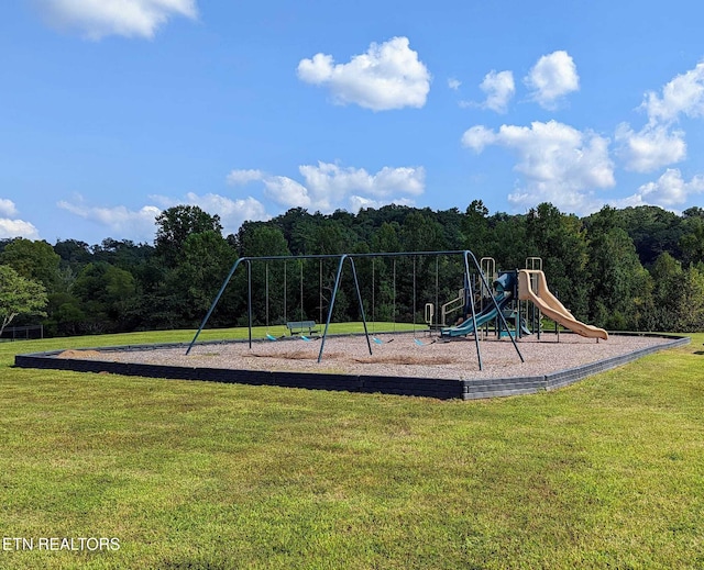 community play area featuring a lawn and a forest view