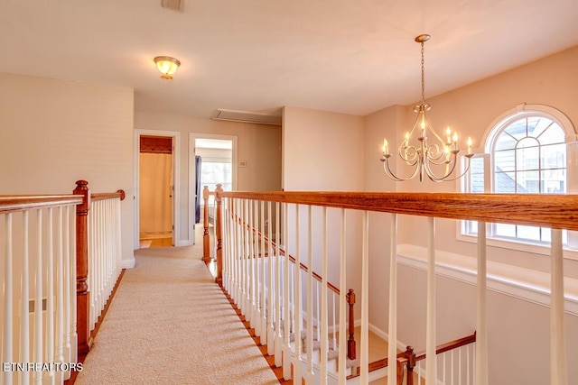hall with a wealth of natural light, visible vents, light colored carpet, and an upstairs landing