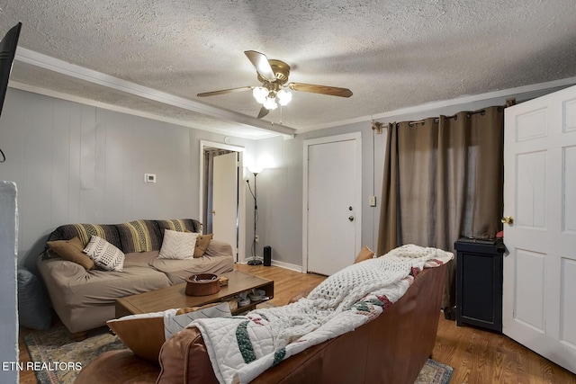 living room with a ceiling fan, crown molding, a textured ceiling, and wood finished floors