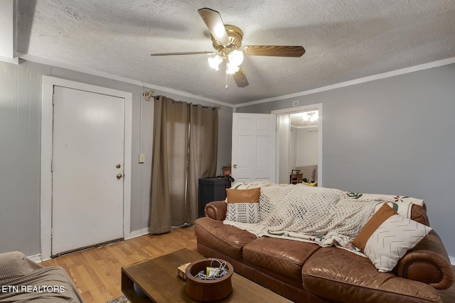 living area with a textured ceiling, crown molding, light wood-style floors, and a ceiling fan