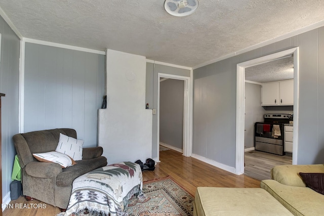 interior space featuring baseboards, light wood-type flooring, crown molding, and a textured ceiling
