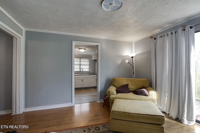 sitting room featuring ornamental molding, a textured ceiling, and wood finished floors