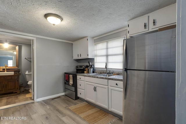 kitchen with white cabinetry, a sink, stainless steel appliances, and light wood-style floors