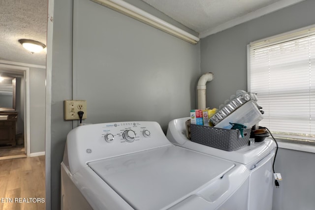 clothes washing area featuring washing machine and clothes dryer, a textured ceiling, baseboards, laundry area, and light wood-type flooring