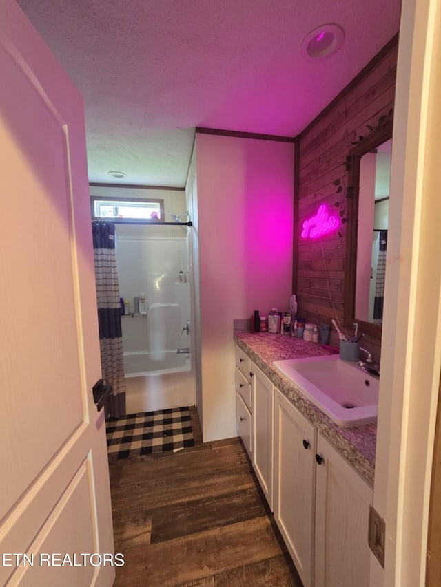 bathroom featuring shower / bath combination with curtain, wooden walls, vanity, and wood finished floors