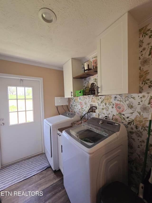 washroom with dark wood finished floors, a textured ceiling, wallpapered walls, cabinet space, and washer and clothes dryer